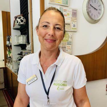 Receptionist at Hotel Ausonia in Rimini, wearing a white shirt with the hotel logo.